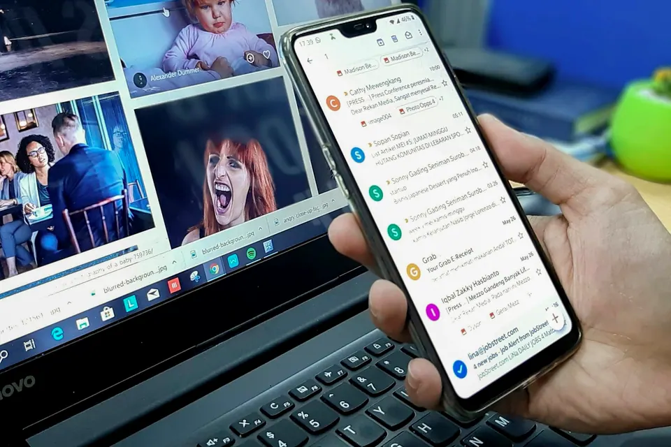 Человек просматривает сообщения на смартфоне рядом с ноутбуком