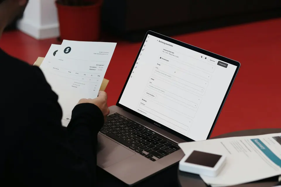 Человек работает с документами, ноутбуком и телефоном за столом